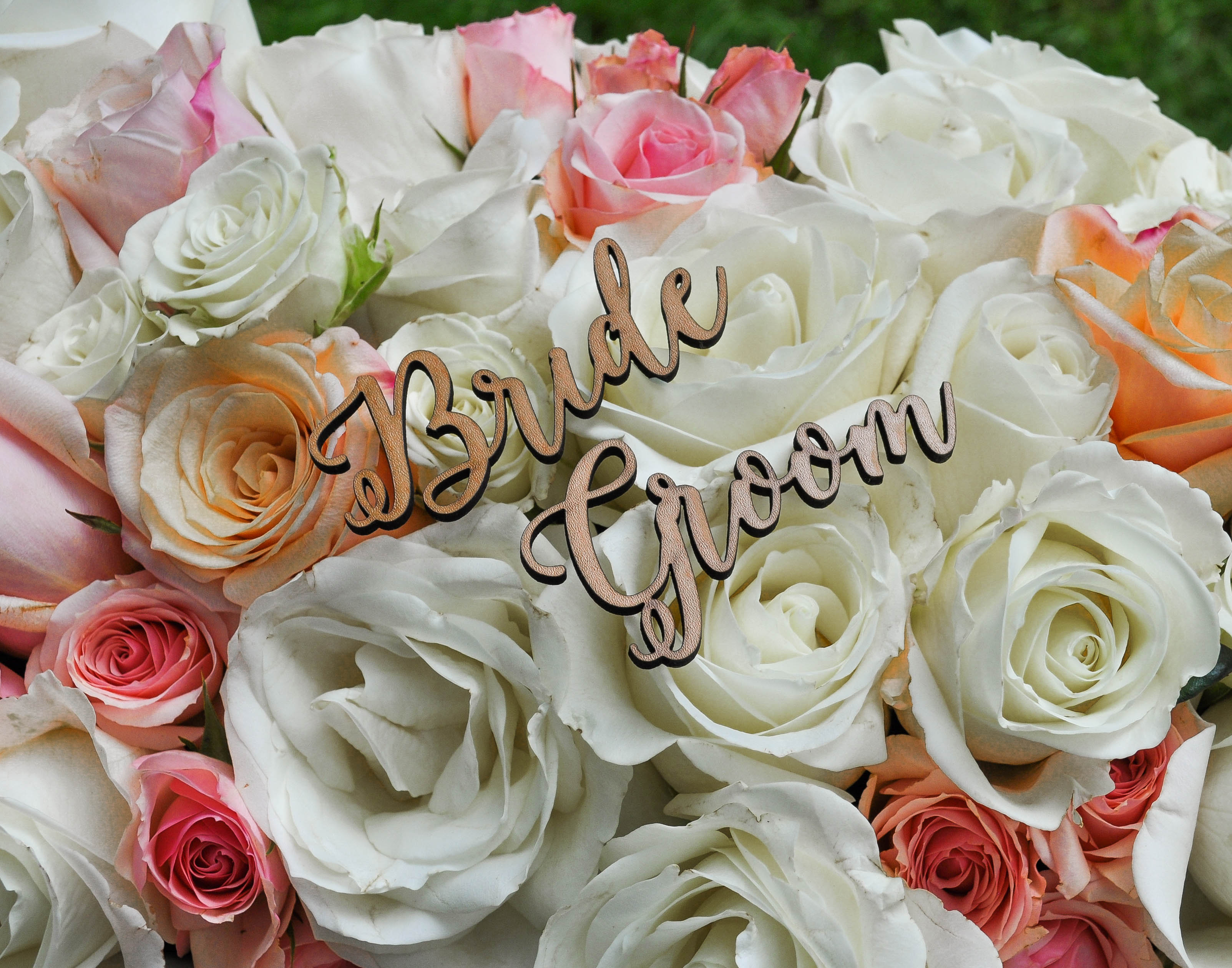 Close up of white and pink roses with Bride and Groom signs